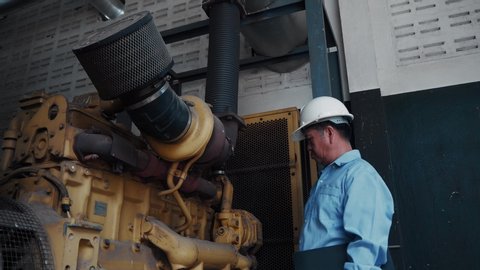 An asian senior engineer or mechanic checking on industrial power generator low angle shot in factory