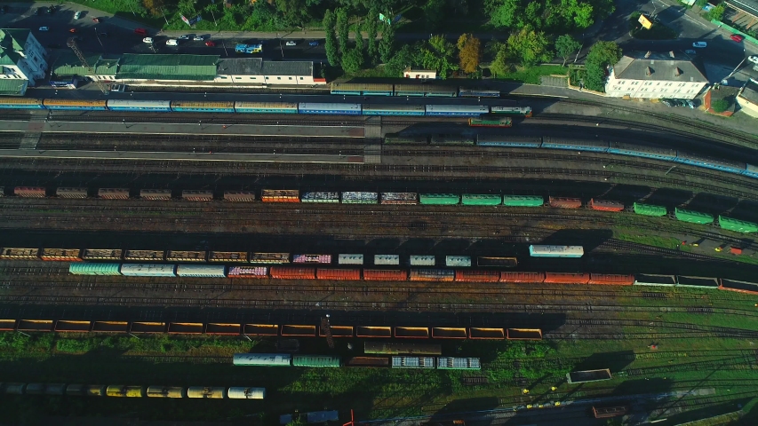 Aerial view of colorful trains on the railway station. Wagons with goods on railroad. Heavy industry.