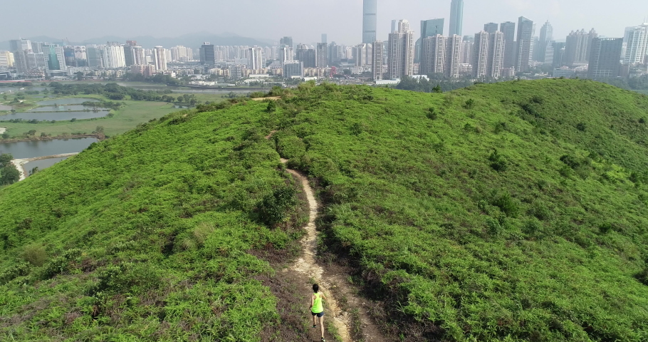 Aerial view of female ultramarathon runner running on mountains in hong kong next to shenzhen city,China