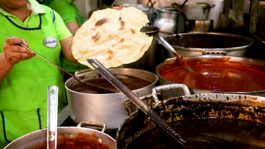 Woman put some sauce on the tortilla. Local woman selling street food at a traditional market. Local food. Tortilla preparation. Oaxaca, mexico