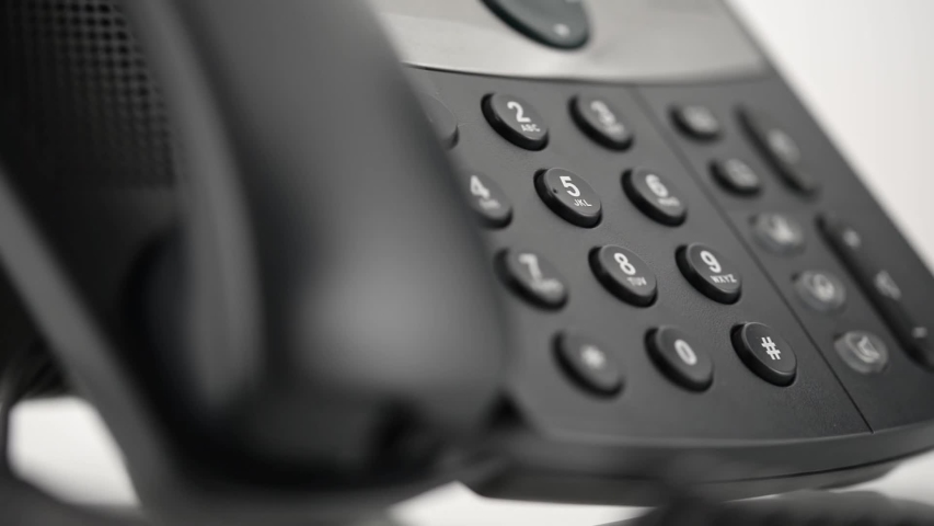 Low angle closeup view of male hand picking up handset and dialing telephone number on black landline phone keypad. Royalty-Free Stock Footage #1037982029