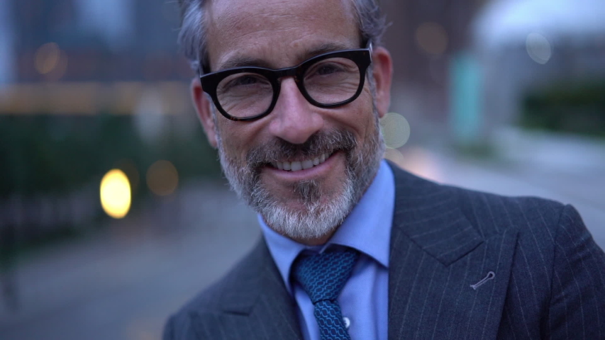 Slow motion of successful mature entrepreneur in expensive clothing posing in financial district with crossed hands and sincere smile on face, happy middle aged banker standing at urban setting 
 | Shutterstock HD Video #1037982773