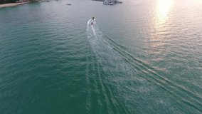 Banana boat adventure scene aerial video by drone. drone view. sea view. blue sea. green sea. yellow boat. high speedboat. boat and wave. rubber boat