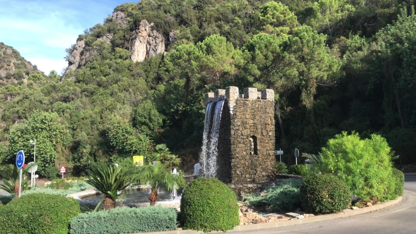 Fountain made of stone bricks in Benahavis town Andalucia, Spain. Water runs down the walls of the tower and the rim of the tower are splashing water springs.