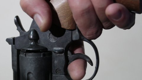 close-up man's hand holds the gun in his hand, loads and pulls the trigger