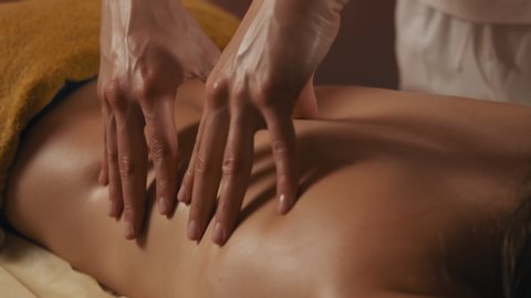 Young woman having massage in spa salon. Close-up of woman relaxing during back massage lying on massage table in slow motion. 4k, UHD