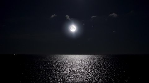 Full moon at night reflecting on the water. Alpha channel moonlight bright sea reflection. Clear big distinct moon glowing over the ocean in eerie night scene.