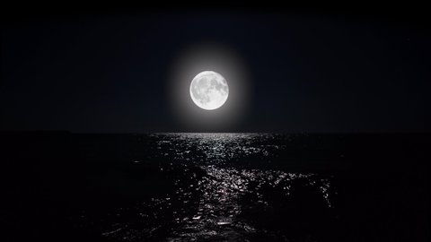 Big full moon at night reflecting on the water. Alpha channel moonlight bright sea reflection. Clear big distinct moon glowing over the ocean in eerie night scene.