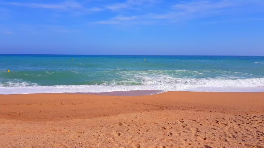 The sea is worried and runs onto the sandy shore under sun