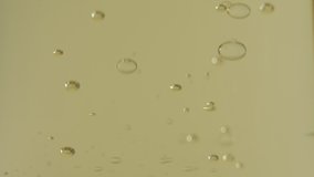 Transparent bubbles floating in the gold liquid. Close up. Slow motion.