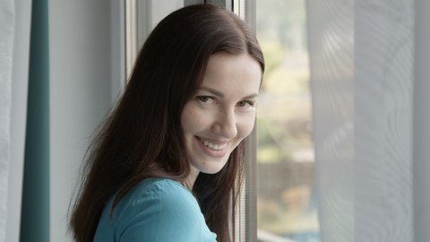 Portrait of a Smiling Female standing by the Window Shot on Red
