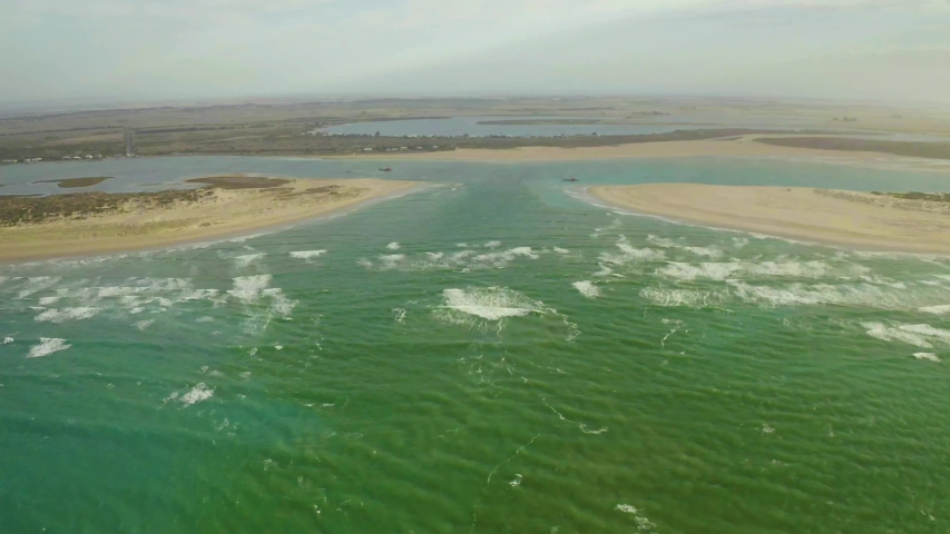 Drone video of Murray Mouth, Coorong, South Australia, Australia, travelling from the sea through the Murray mouth and over dredging equipment, ending at family with dog