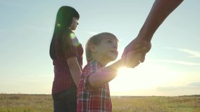 happy family little boy a holds parents hand walking go slow motion video concept. happy lifestyle teamwork dad man mom girl and son boy child hold hands walk go on field in nature .happy family