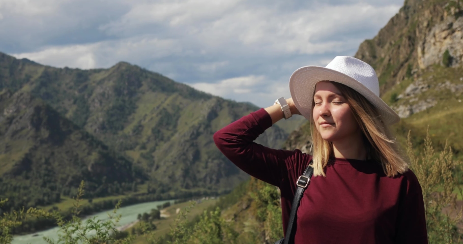 Portrait of youg woman traveller hiker with map enjoying nature standing in mountains valley breathing fresh air. Hiking, eco tourism and travelling concept. Blonde girl tourist in hat in nature park.