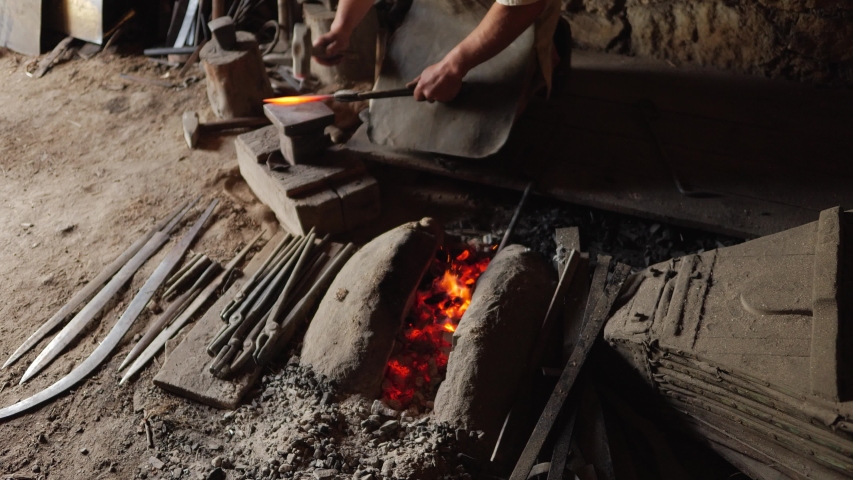 blacksmith working hot metal with hammer on the anvil in the forge