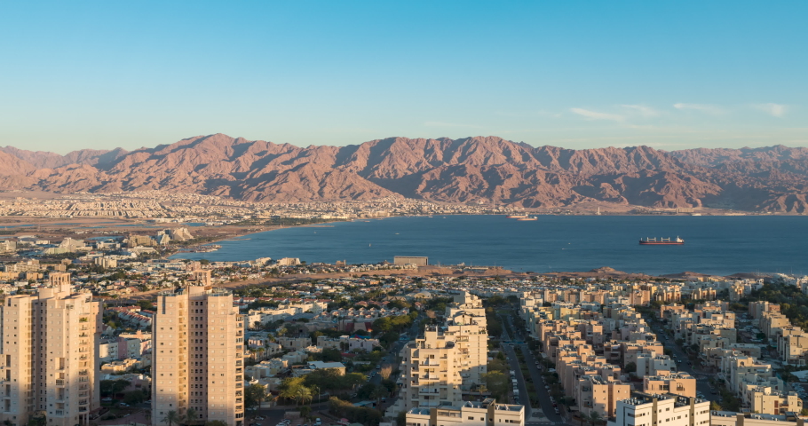 Panoramic aerial Timelapse view of eilat coastline at evening, with Ships anchoring at the red sea, israel. At the distance is the city of Aqaba, Jordan and the moav mountains