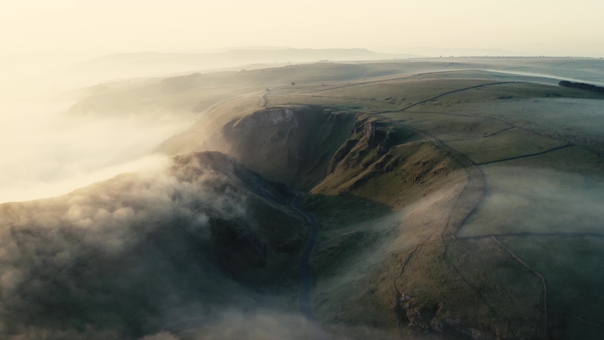 a drone revealing the rolling mist/ cloud inversion over Winnats pass, caslteton peak district. sunrise over hope valley