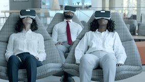 Relaxed business team in vr headsets. Professional multiethnic business colleagues sitting on chairs and using virtual reality headsets in office. Business and innovation concept