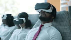 Business colleagues using virtual reality headsets. Close-up view of multiethnic professional business colleagues sitting on chairs in vr headsets. Business and technology concept