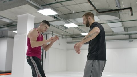 Two wrestlers perform in slow motion. Greco-Roman wrestlers train in the hall in T-shirts and coats.
