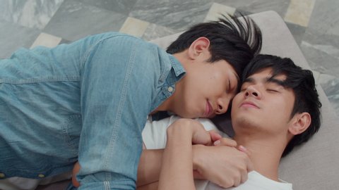 Young Asian gay couple sleep together at home. Teen korean LGBTQ men happy relax rest lying on bed in bedroom at house in the morning. : vidéo de stock