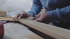 a carpenter measures a wooden board with a square at an angle and marks the dimensions with a pencil. 4k. 4k video. slow motion. 24 fps