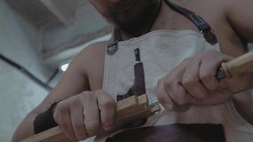 a carpenter carves a dovetail on a wooden part with a chisel, holding it in his hands. a joiner processes a wooden board. 4k. 4k video. slow motion. 24 fps
