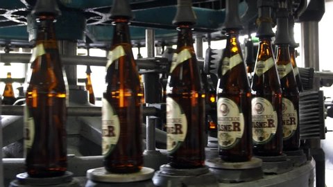 Brewery. Production shop for bottling beer. Bottles of dark glass filled with beer move inside the labeling machine. The process of labeling a bottle. Shymkent /Kazakhstan - September 21, 2019.
