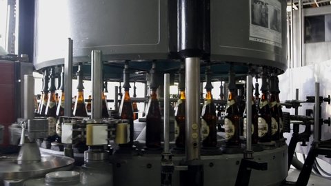 Brewery. Production shop for bottling beer. Bottles of dark glass filled with beer move inside the labeling machine. The process of labeling a bottle. Shymkent / Kazakhstan - September 21, 2019.