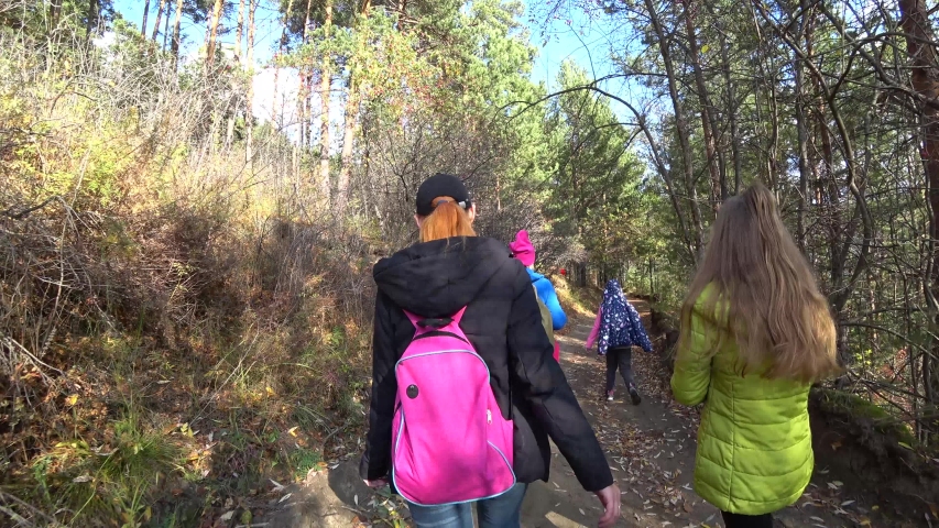 Tourists, different ages, walk along a forest path on a mountainside. Autumn. Concept of hiking, walking for health.