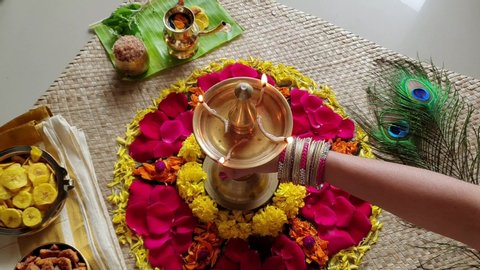 Woman lighting lamp with hand and traditional flower bed for Onam harvest festival of Kerala India. Video of fresh flower carpet floral pattern made for Vishu, dussehra, dasara, diwali celebration. 
