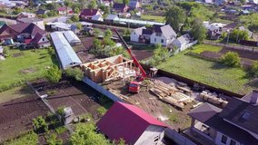 Village with wooden house under construction. Clip. Top view of process of construction of wooden house on background of neighboring country cottages