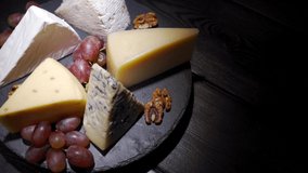 Assorted cheeses with nuts and fruits on the table. Rotating video