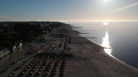 Landing aerial drone video, bird's eye view along shoreline of Gromitz (Germany) beach. Sunrise, early morning.