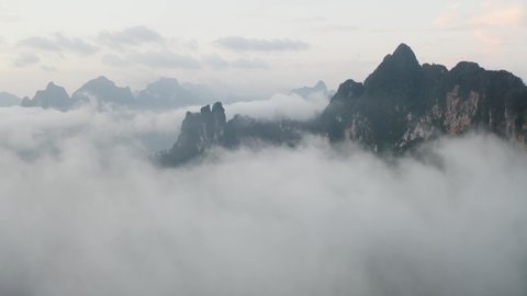 4K Aerial Drone Shot Above the clouds in Khao Sok National Park. Reveal shot of boat house on a quiet lake in Thailand