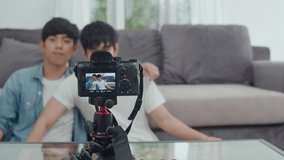 Young Asian gay couple influencer couple vlog at home. Teen korean LGBTQ men happy relax fun using camera record vlog video upload in social media while lying sofa in living room at house. Slow motion
