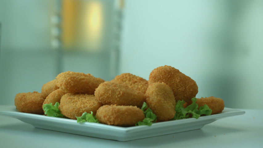 Appetizing tasty yellow chicken nuggets fall into the breakfast plate. The concept of nutritious high-calorie food. Harmful and fatty foods. Slow motion Royalty-Free Stock Footage #1038087515