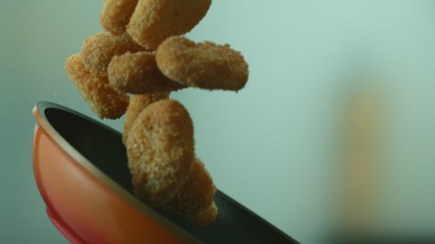 Close-up of delicious golden chicken nuggets fried in a pan and fly up in the air during cooking. The concept of professional cooking or home menu. Slow motion