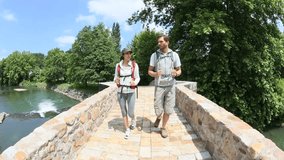 Couple with backpack walking on stone bridge
