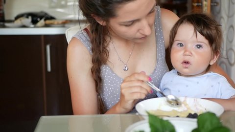 mom feeds the baby from a spoon. Mom feeds baby from spoon. Little boy eats healthy food 