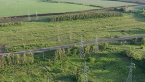 Country road with cars moving and high voltage lines towers, aerial video