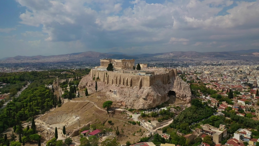 Aerial video of unique Masterpiece of Ancient times the Parthenon on top of iconic Acropolis hill with beautiful clouds and blue sky, Athens, Attica, Greece