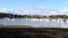 Kirkcudbright harbor in Dumfries and Galloway in Scotland. Scenic 4K resolution stock video of waterfront on sunny day. Blue sky with several white boats in the marina. Irish sea in Scotland.