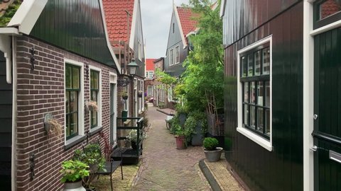 Footage of old, historical, traditional houses and cobblestone street in a small fishing town called Volendam near Amsterdam. Camera moves forward.