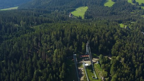 Aerial view around the village Hinterzarten in Germany in the black forest on a sunny day in summer. Pan to the left away from the ski jump hill.