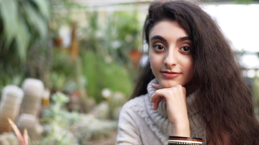 Portrait of young attractive lady with big eyes and long curly hair looking into the camera