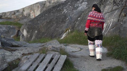 Rear view of female in national Greenlandic dress walking on mountain - Disko Bay, Greenland