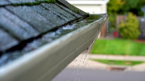 Roof gutters clogged with leaves and overflowing water slow motion