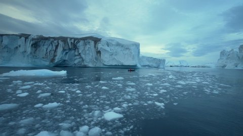 Pan Left to Right: Small Boat Traversing the Waters of Greenland Disko Bay With Small Chunks of Ice Floating in the Area