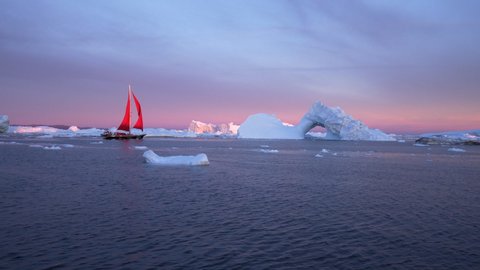 Boat moving towards iceberg with natural arch - Disko Bay, Greenland